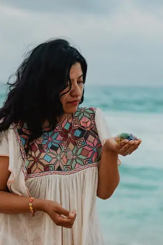 Retrato de Blanca contemplando un cuarzo en su mano, huipil bordado a mano, junto al mar